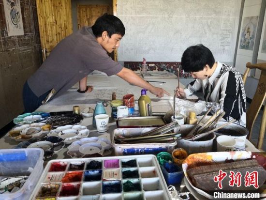 圖為2020年8月下旬，敦煌“80后”畫家張杰龍(左)在為云南麗江“學生”莫北講解敦煌壁畫的繪畫技巧?！●T志軍 攝