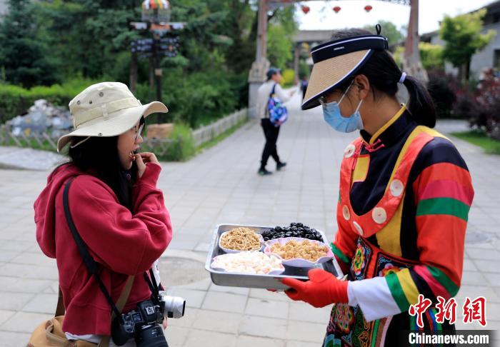 圖為身穿土族服飾的女性介紹當地特色小吃。 薛蒂 攝 圖為身穿土族服飾的女性介紹當地特色小吃。 薛蒂 攝