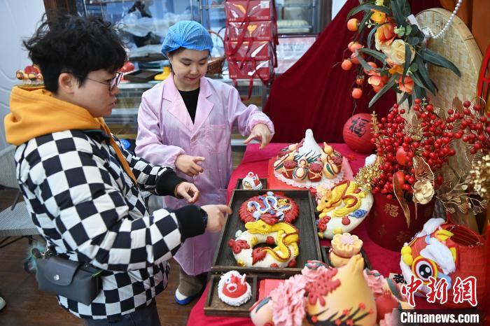 1月25日,隨著春節(jié)臨近,蘭州一花饃店“龍”元素花饃熱銷。圖為工作人員向顧客推薦“龍”元素花饃。九美旦增 攝</p><p> 1月25日,隨著春節(jié)臨近,蘭州一花饃店“龍”元素花饃熱銷。圖為工作人員向顧客推薦“龍”元素花饃。九美旦增 攝</p><p>